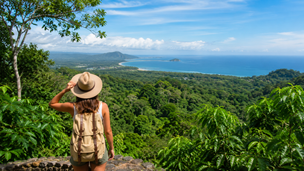 Traveler overlooking a lush Costa Rica rainforest and coastline during a sustainable adventure vacation